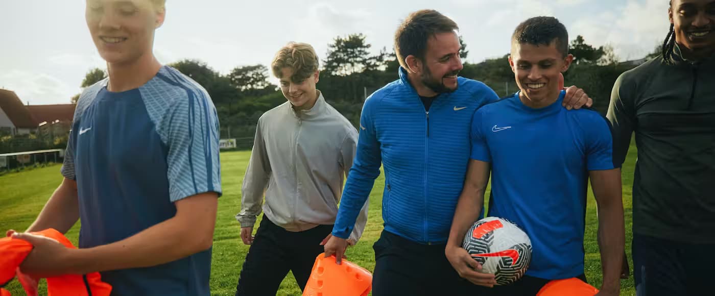 Jongeren en trainer lopen over het sportveld