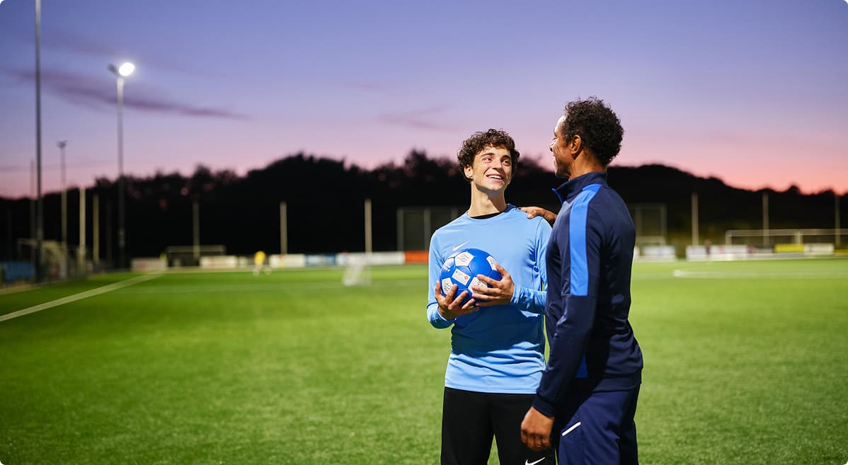 Een jonge voetballer op het veld met zijn coach